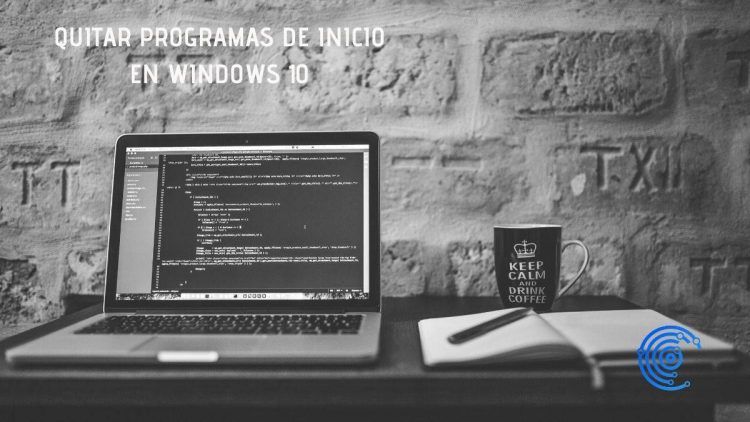 Fotografía en blanco y negro de un escritorio con ordenador y libreta junto a una pared