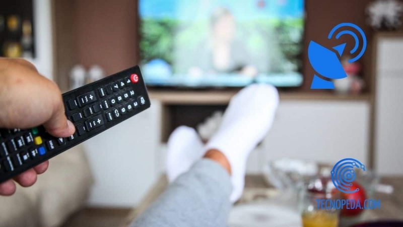 Hombre con los pies en la mesa viendo la tv