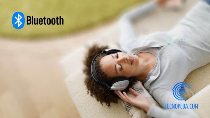 Mujer tumbada oyendo música por unos auriculares bluetooth