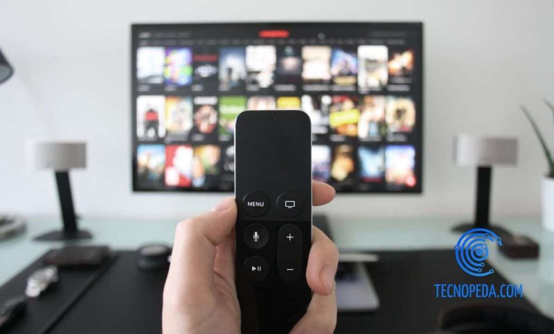Control remoto en primer plano con televisión de fondo
